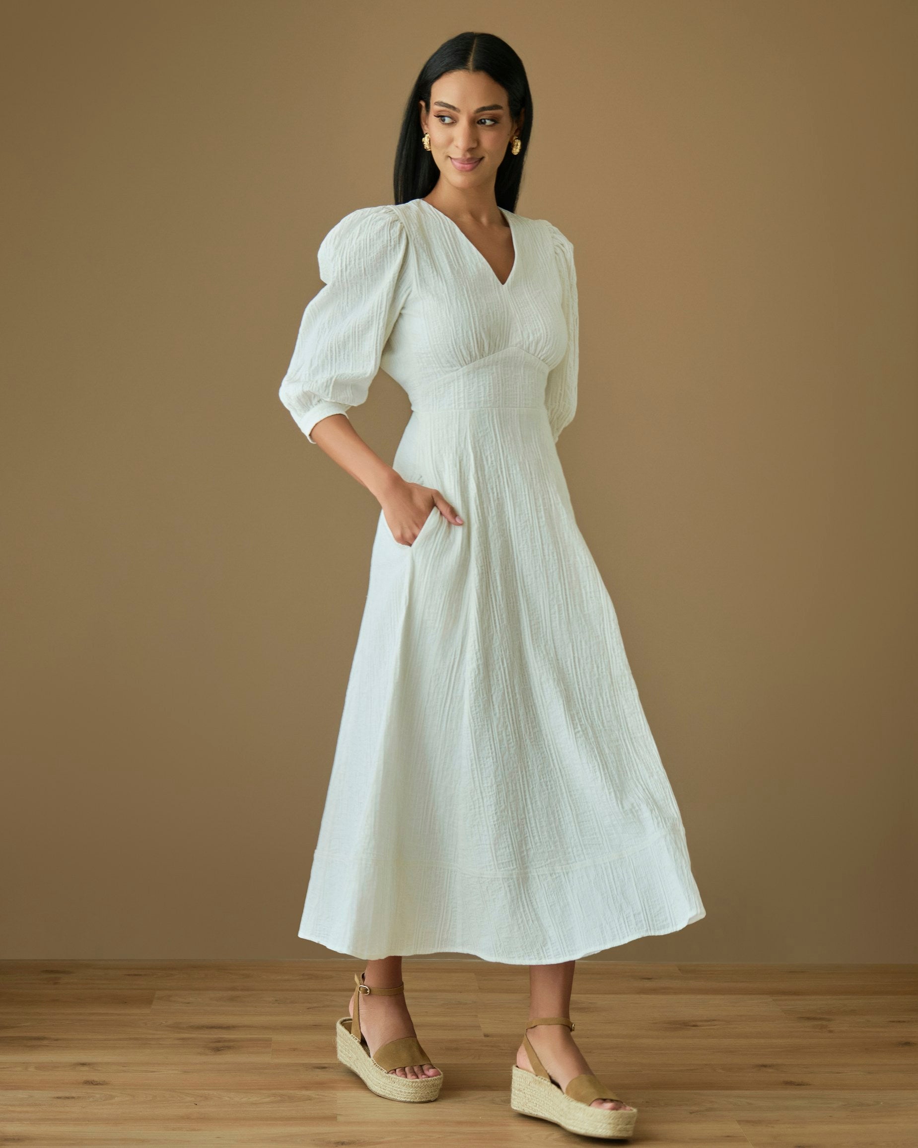 Nalla cotton dress in white, featuring puff sleeves and a midi length, worn by a model with stylish platform sandals.