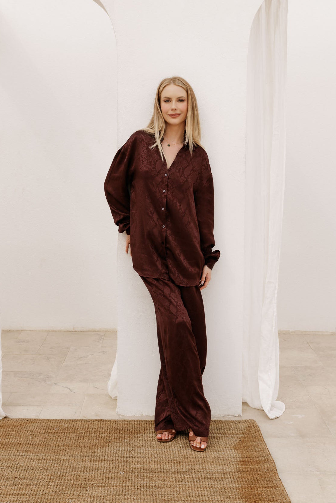 Premium women’s satin two-piece set in rich burgundy, combining a draped button-down top and wide-leg trousers for sophisticated holiday looks.