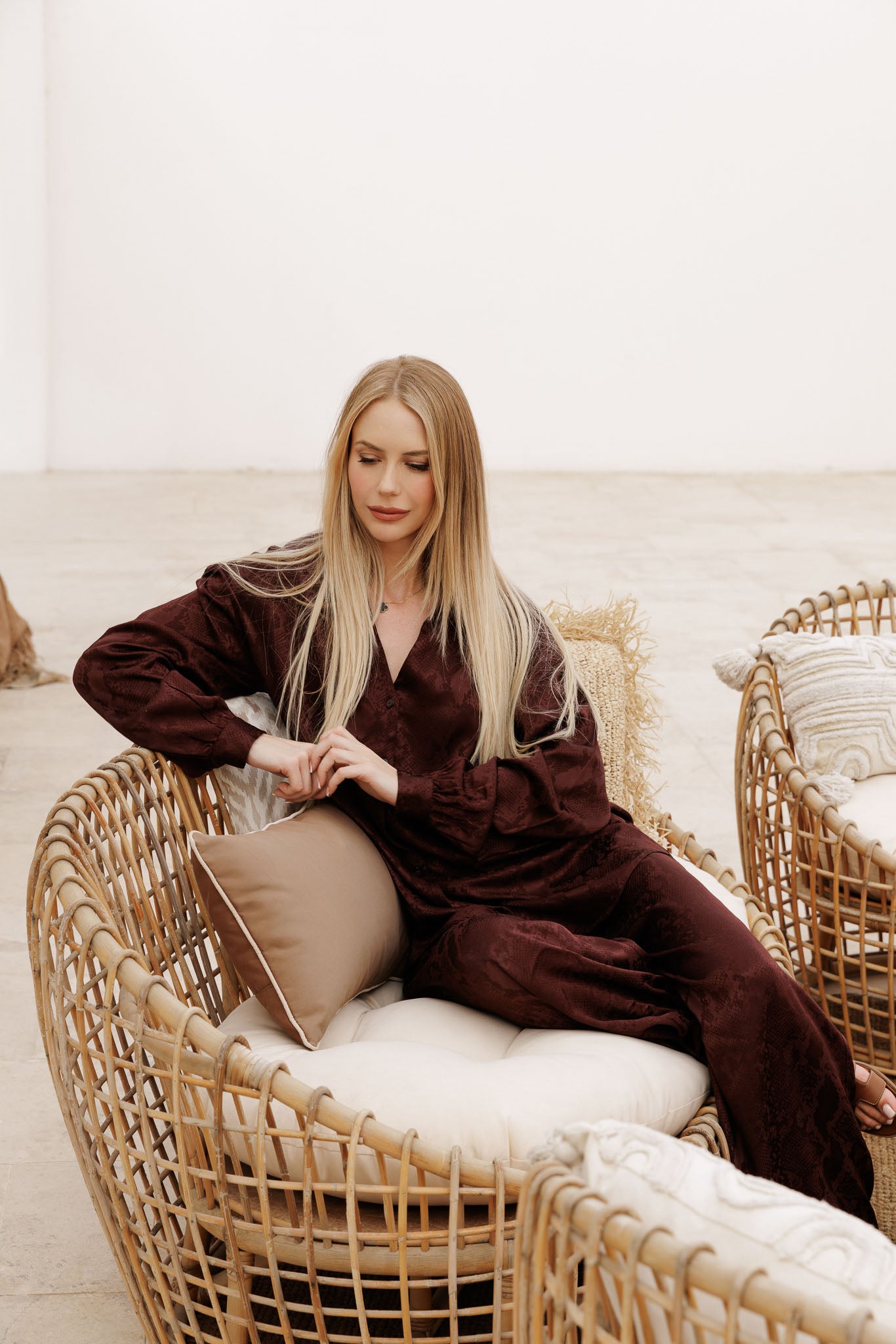 Elevated satin co-ord in deep wine burgundy with subtle pattern, featuring a loose-fit shirt and relaxed wide-leg pants for chic vacation wear.