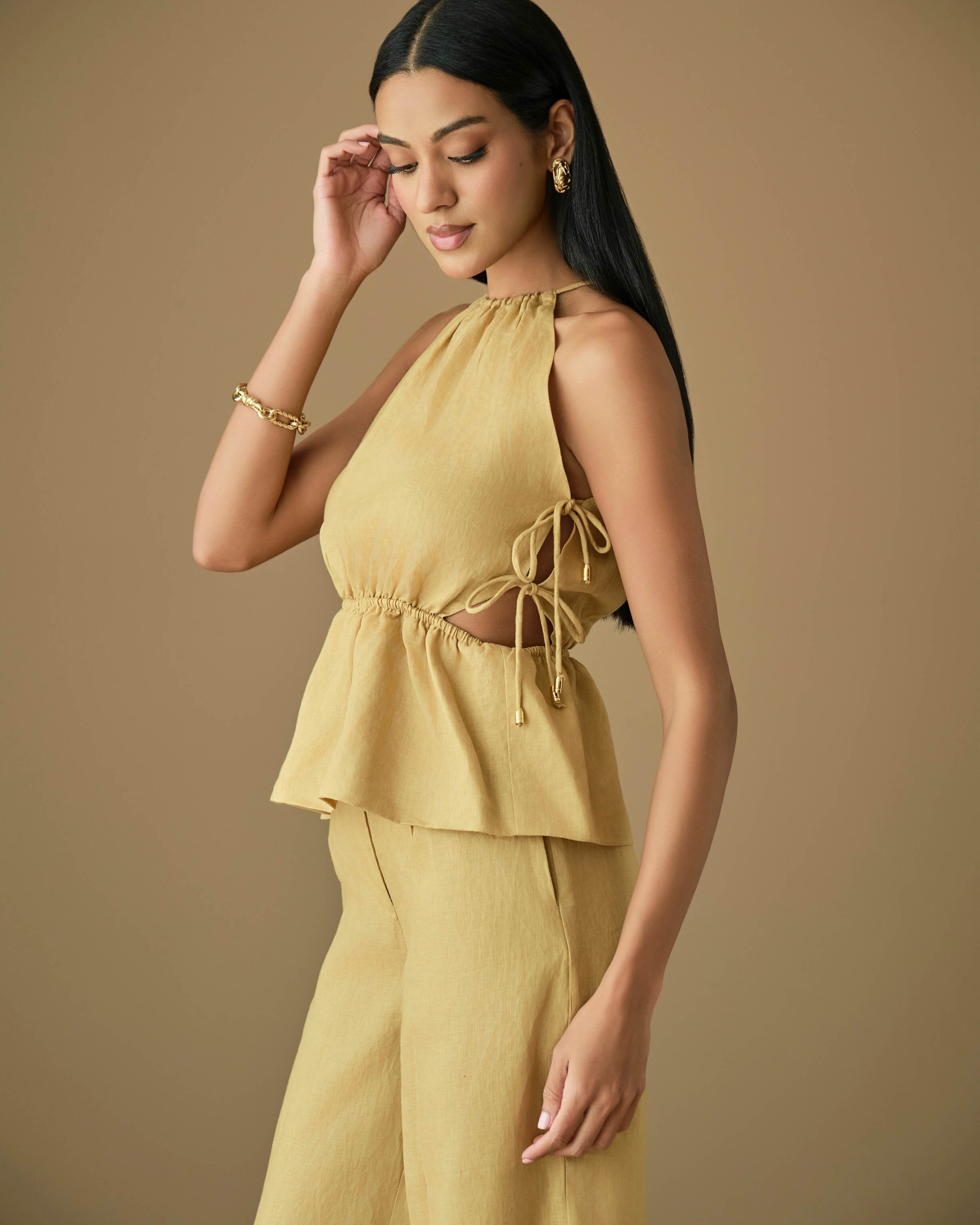 Model showcasing a chic, mustard-colored linen top with a peplum waist and relaxed fit, styled elegantly.