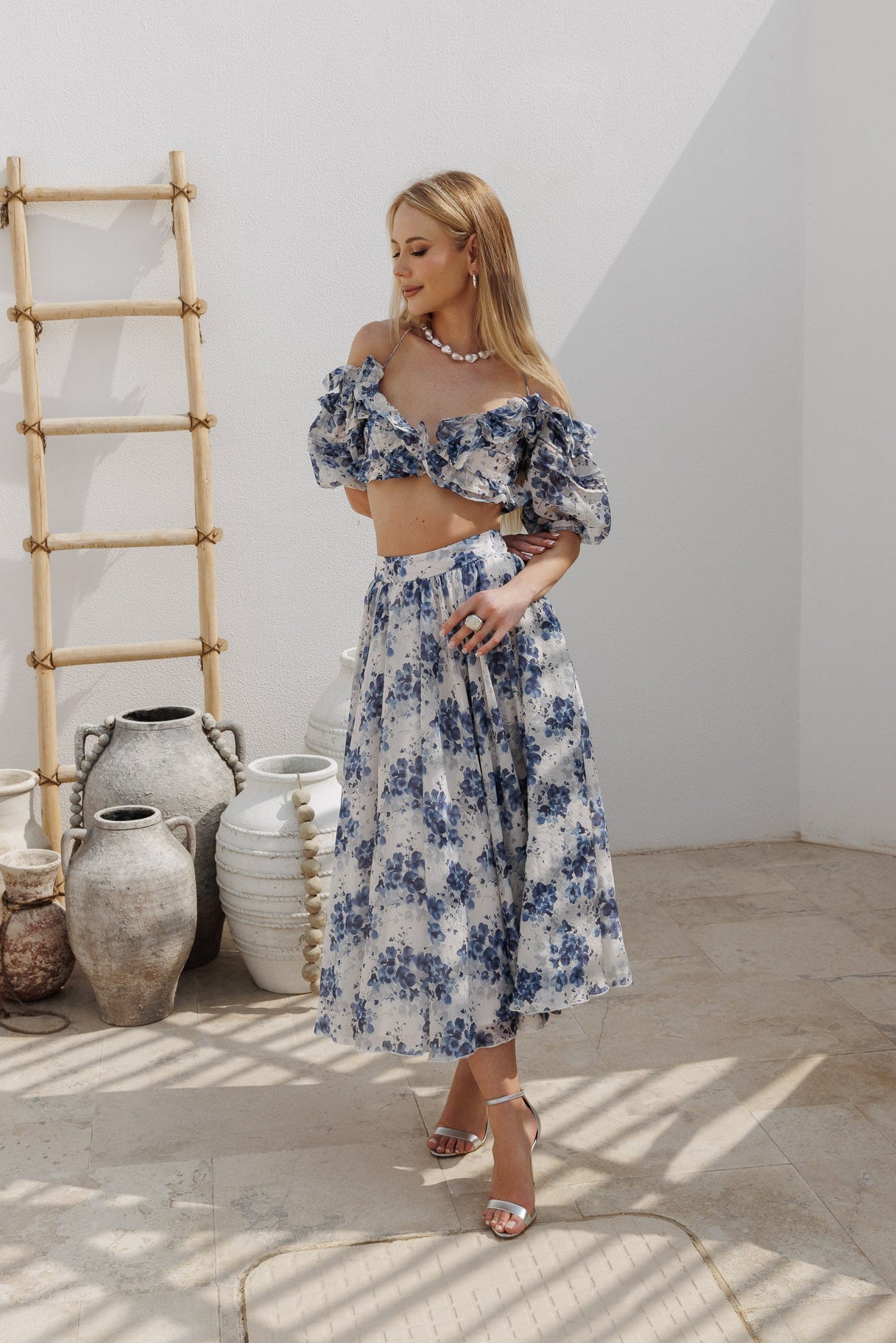 Blue floral two-piece set featuring an off-shoulder ruffled crop top and a high-waisted midi skirt.