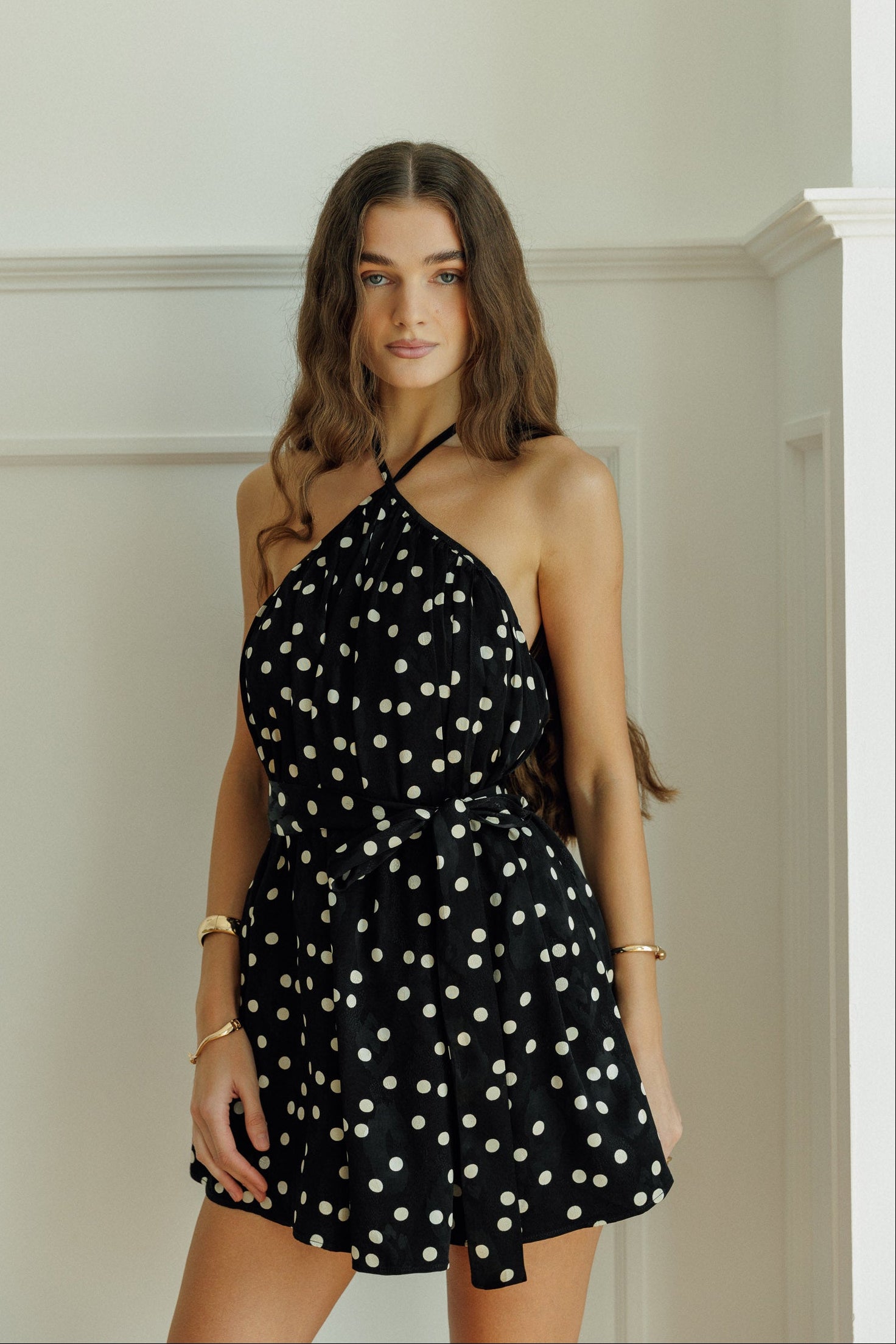 Woman wearing the Anaya black polka-dot halter mini dress.