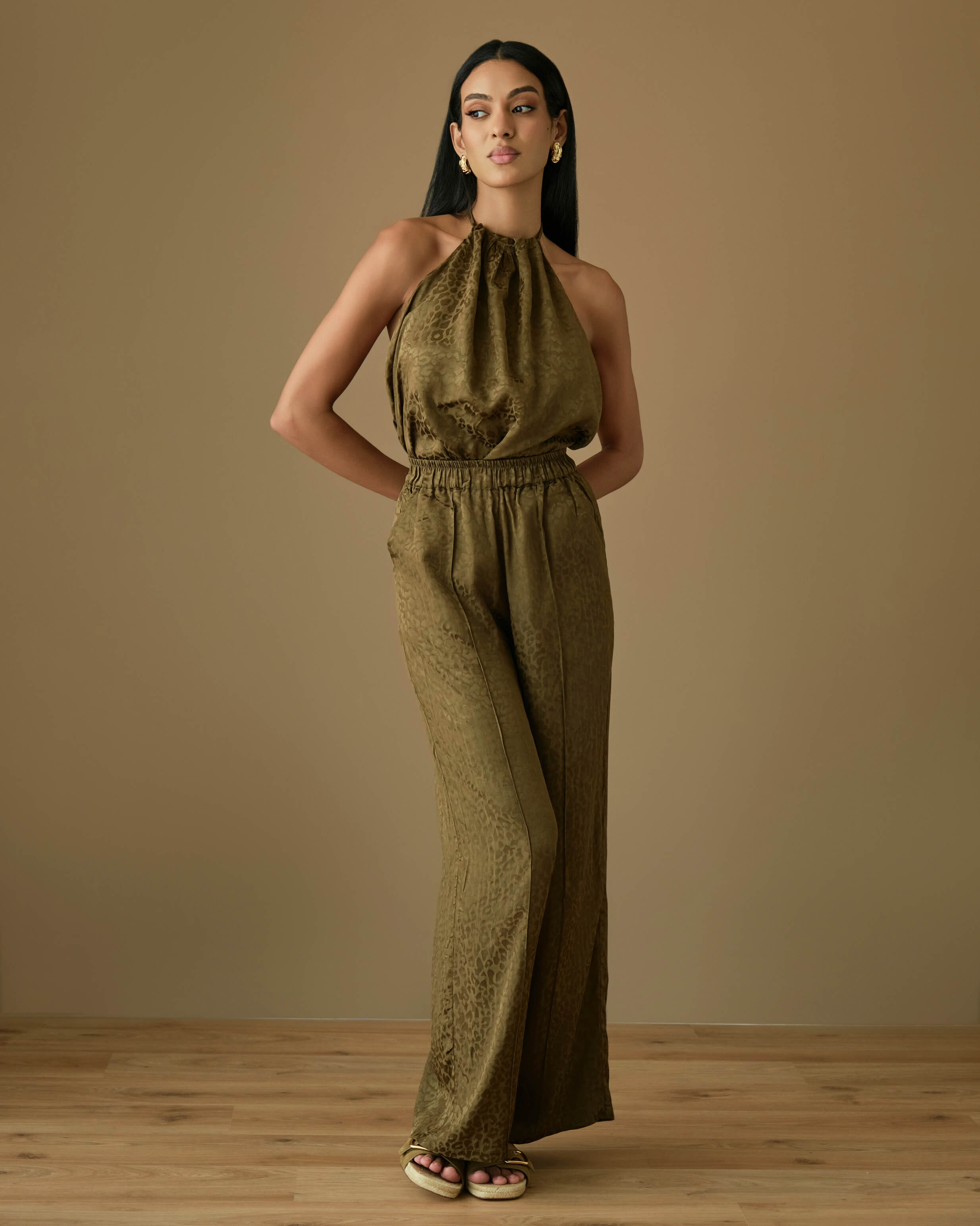 Olive viscose two-piece set featuring a halter neck draped top with soft gathers at the neckline, paired with high-waisted wide-leg trousers with an elasticated waistband. Lightweight, fluid viscose fabric with a silky feel and elegant drape, perfect for effortless resort and evening styling.