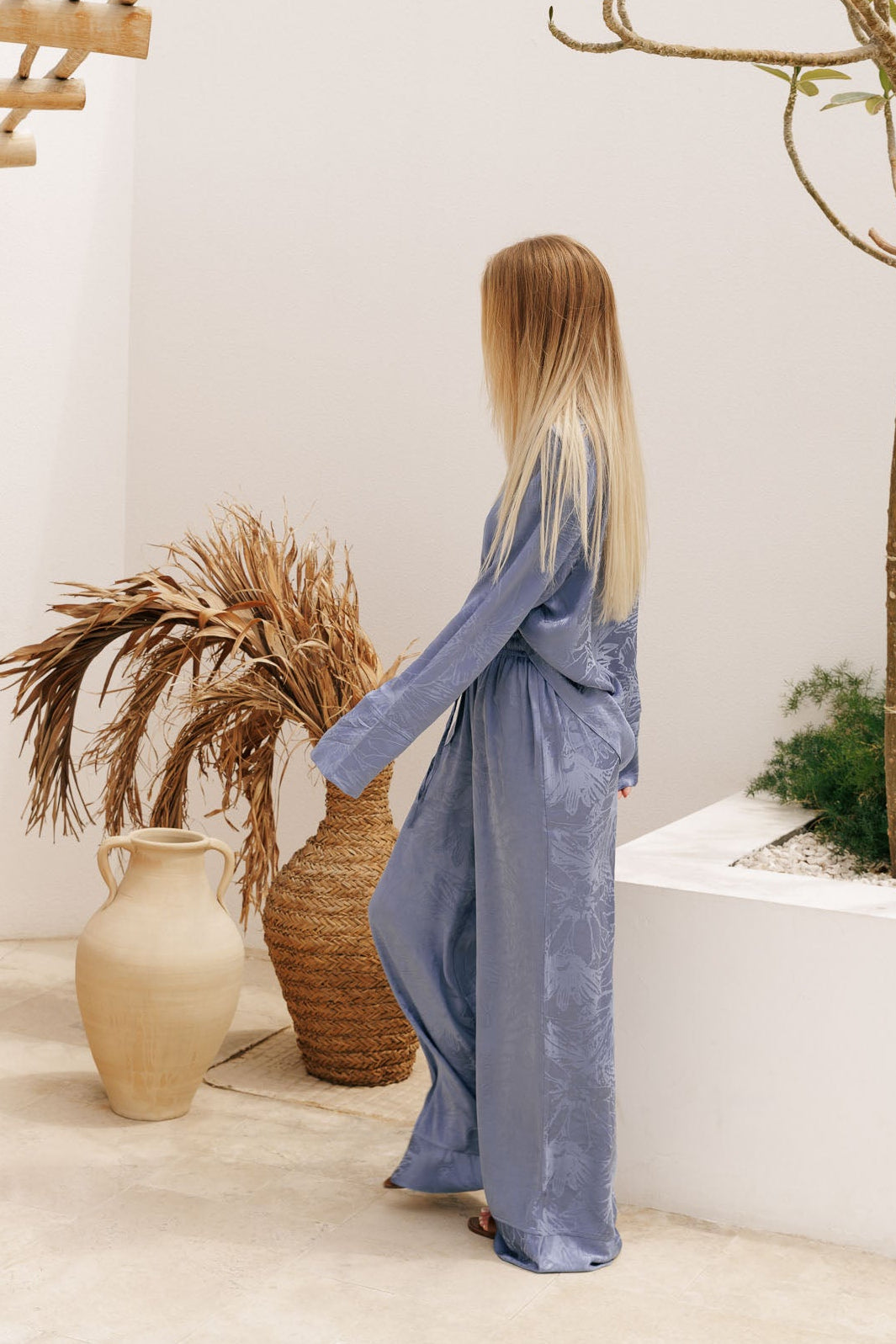 Elevated resortwear co-ord in silky blue fabric with subtle pattern, combining a loose-fit shirt and relaxed pants for modern vacation style