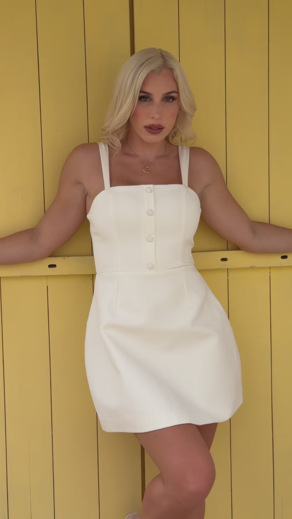 White A-line mini dress with a fitted bodice, square neckline, slim straps, button-front detail, and a softly flared skirt for a clean, feminine silhouette.